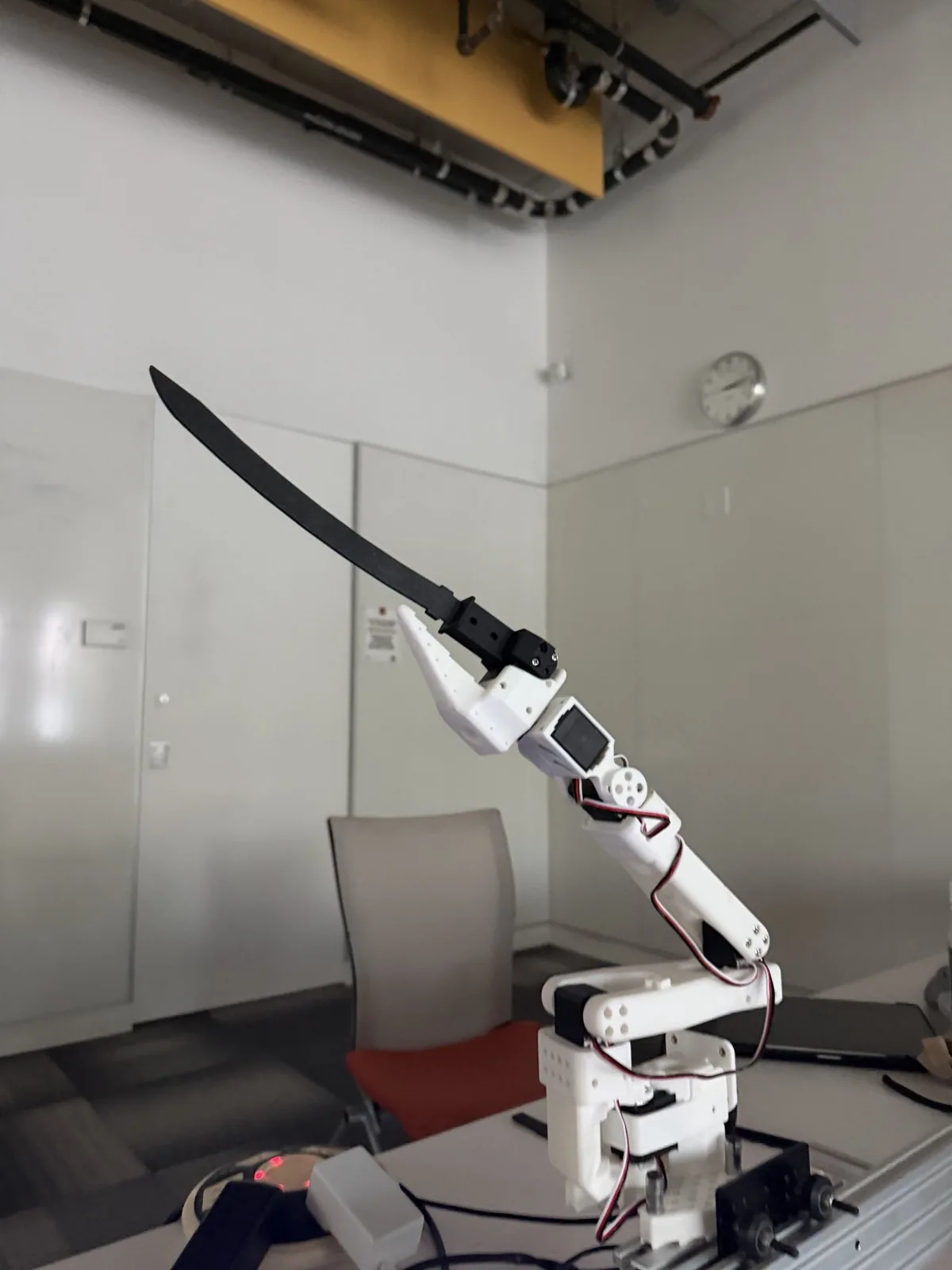 The arm holding a black printed blade, raised over the rail